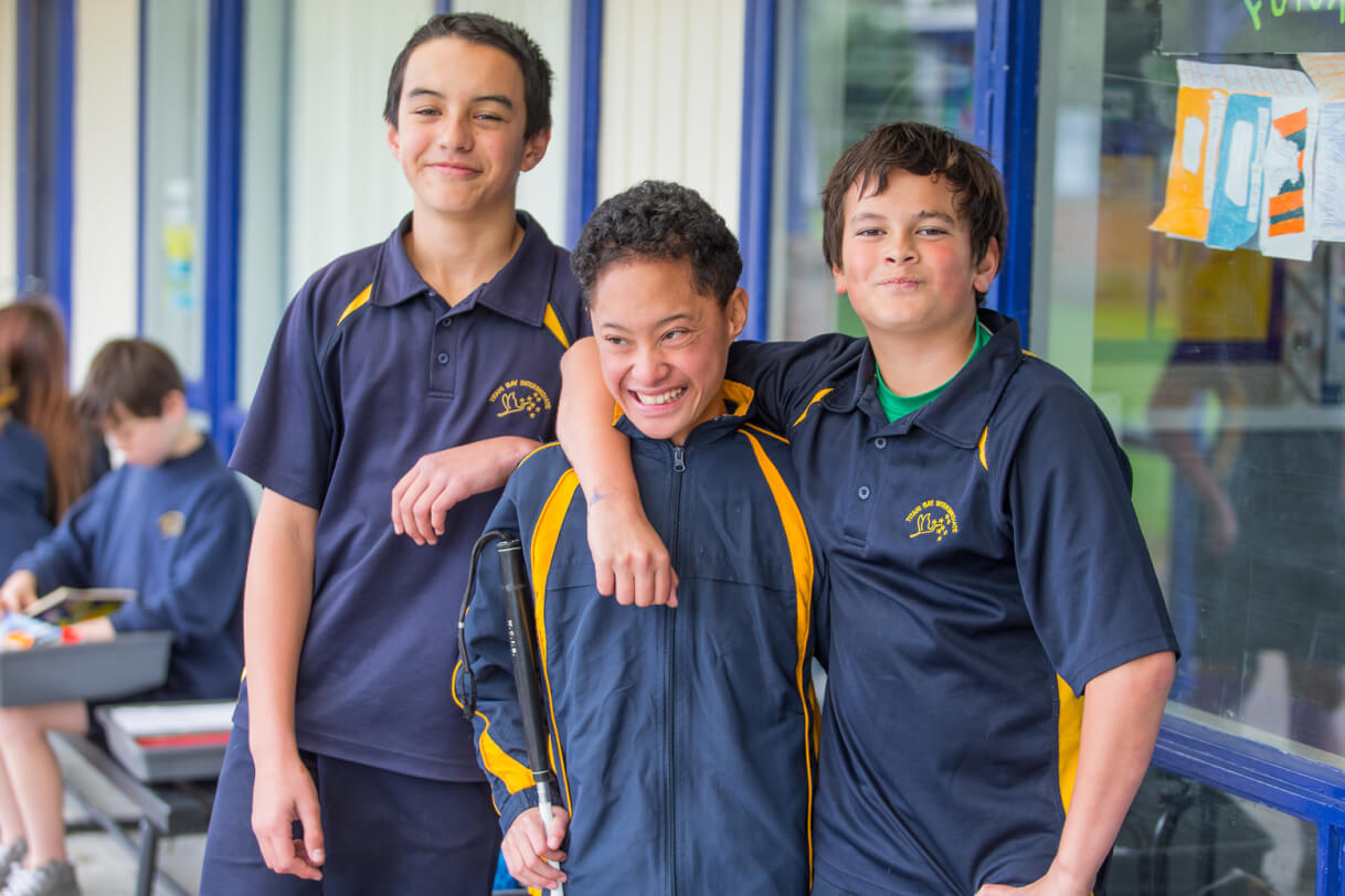 Boston and two friends stand outside the classroom.