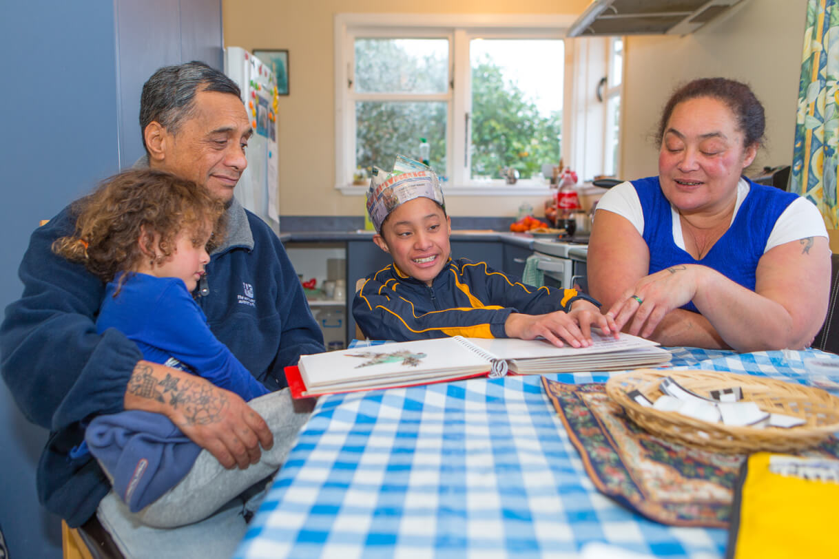 Boston reads with his family at the dining table.