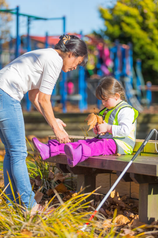 Giana sitting on a bench holding an autumn leaf.