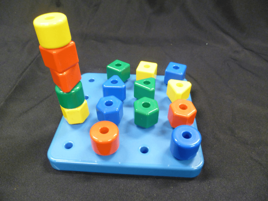 A set of four shapes in four colours to place into holes in a 4X4 board. Five of the pegs are stacked while the remainder are in individual holes.