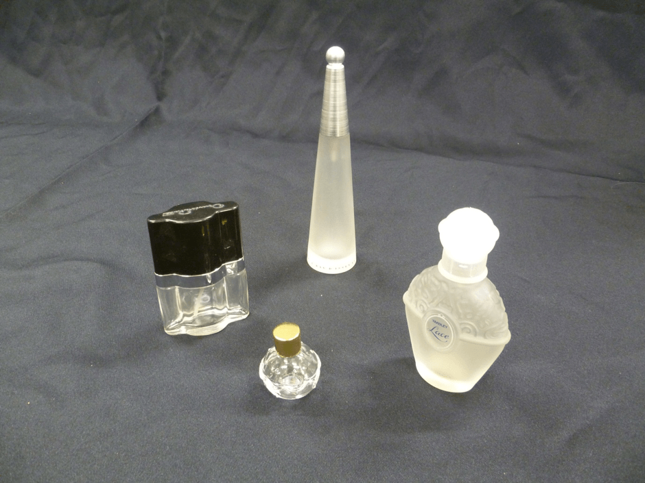 Four perfume bottles of different shapes and sizes with lids.