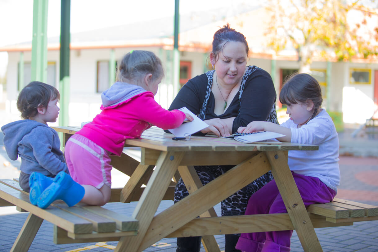 Gina and her family reading at the picnic table.