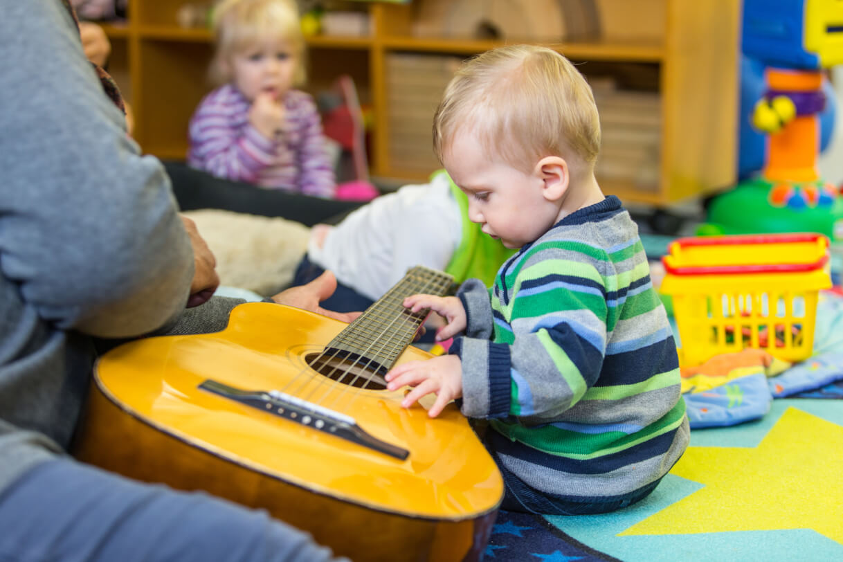 Robert sits to the right of a guitar and explores with his hands.